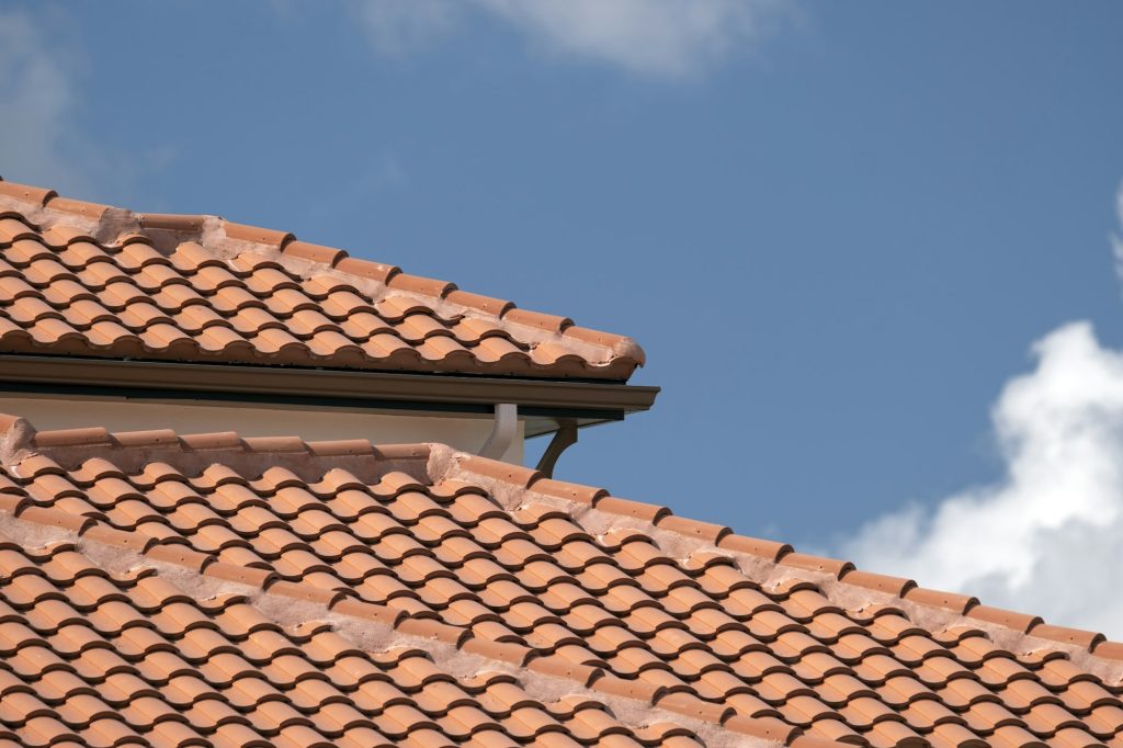 Overlapping rows of yellow ceramic roofing tiles covering residential building roof